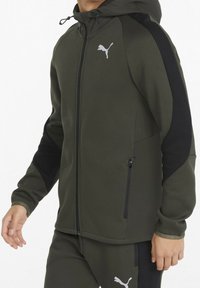 Donkergroene gewatteerde jas met een gladde textuur, zwarte zijpanelen, een rits aan de voorkant en een wit Puma-logo op de borst.
