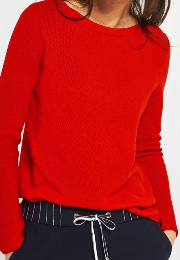 Roter strukturierten Pullover mit langen Ärmeln und Rundhalsausschnitt, kombiniert mit marineblauen Hosen mit weißen vertikalen Streifen und Kordelzugdetails.