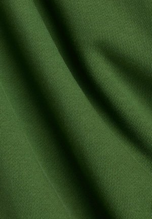 Grönt tyg med en slät, ribbad struktur och ett jämnt stickmönster. Mjuka veck framhäver dess lätta och mångsidiga egenskaper.