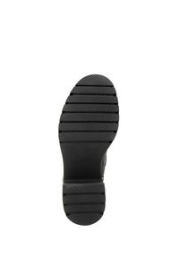 Black rubber shoe sole featuring a grooved texture with horizontal and vertical patterns for traction. Rounded toe with a flat heel.