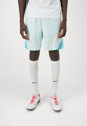 Shorts de sport bleu clair avec une accentuation bleu foncé, chaussettes blanches arrivant aux genoux, et chaussures de football blanches avec des lacets rouges et des détails noirs.