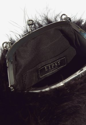 Juodas dirbtinės kailio delninukas su blizgančiu sidabro rėmo užsegimu. Vidus pamuštas juodu audiniu, su pridėtu prekės ženklo žyme.