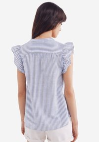 Blouse en coton rayé avec des manches courtes à volants, un dos froncé et un schéma de couleurs bleu clair et blanc.
