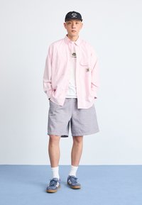 Light pink button-up shirt, white graphic t-shirt, striped shorts, navy sneakers with white stripes, and white socks. Simple and casual attire.