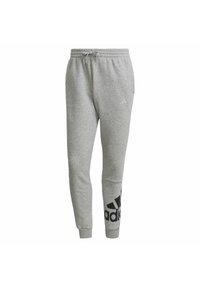 Szare dresy wykonane z miękkiego materiału, z elastycznym pasem, bocznymi kieszeniami oraz dużym czarnym logo Adidas na lewym nogawce.