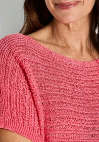 Roze gebreide trui met een losse pasvorm, voorzien van een textuur met ribbelontwerp en een brede halslijn, gemaakt van lichtgewicht, ademend materiaal.