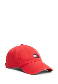 Rød bomulds-baseballkasket med en buet skygge, der har et broderet "TOMMY JEANS" logo-patch på forsiden. Blødt stof og justerbar rem.