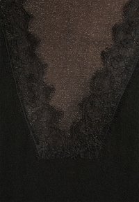Tissu noir avec un panneau en dentelle semi-transparent en forme de V, doté d'une texture subtilement pailletée et d'une bordure florale en dentelle.