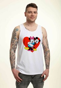 Camiseta sin mangas blanca con un gráfico colorido de Mickey y Minnie Mouse sobre un fondo de corazón rojo. La tela parece suave y tiene un corte relajado.