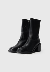 Μαύρες δερμάτινες μπότες μέχρι τον αστράγαλο με στρογγυλή μύτη, μεσαίου ύψους χοντρό τακούνι, πλαϊκό φερμουάρ και λεία υφή. Ραφές στην επάνω πλευρά.