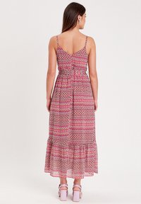 Robe maxi avec fines bretelles, à motifs géométriques roses et jaunes, dotée d'une taille cintrée et d'un ourlet en volants évasés.