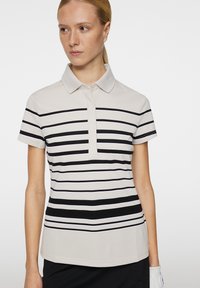 Koszulka polo z poziomymi czarno-białymi paskami, krótkimi rękawami i klasycznym kołnierzykiem, wykonana z lekkiego materiału.