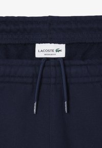 Joggers in cotone blu navy con vita regolabile, caratterizzati da un'etichetta Lacoste e una texture intrecciata, progettati per una vestibilità regolare.