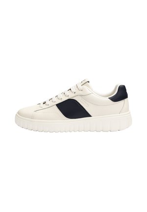 White low-top sneaker with black side panel and heel detail, white laces, and thick white grooved sole.
