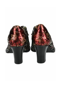 Zapatos de tacón negros con una textura en relieve floral roja brillante. Parte trasera redondeada y tacón negro liso. Presentan un detalle de hebilla en el lateral.