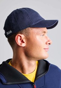 Cappellino blu navy con visiera pre-curvata e regolazione posteriore, caratterizzato da un vistoso logo "SLAM" in grigio chiaro sul retro. Materiale in cotone, design casual.