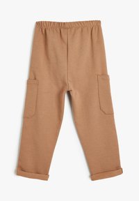 Pantalones de algodón marrón y suave con cintura elástica, dos bolsillos laterales y puños enrollados, que presentan un corte relajado y un diseño minimalista.
