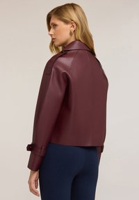 Bordeaux leren jas met een kraag, cropped ontwerp en opgerolde manchetten met een banddetail. Gladde textuur met een slim fit.