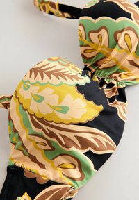 Miękki, czarny stanik z wzorem kwiatowym w odcieniach żółci, zieleni i brązu; elastyczna taśma i regulowane ramiączka.