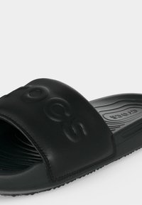 Μαύρο σανδάλι slide με ανάγλυφο λογότυπο "Crocs" στο λουράκι και υφασμένο πάτο για άνεση και κράτημα.