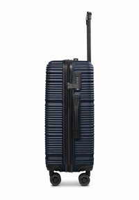 Valise rigide de couleur marine avec texture rainurée, fermeture éclair noire, serrure intégrée et poignée télescopique. Comprend quatre roues pivotantes pour une mobilité optimale.