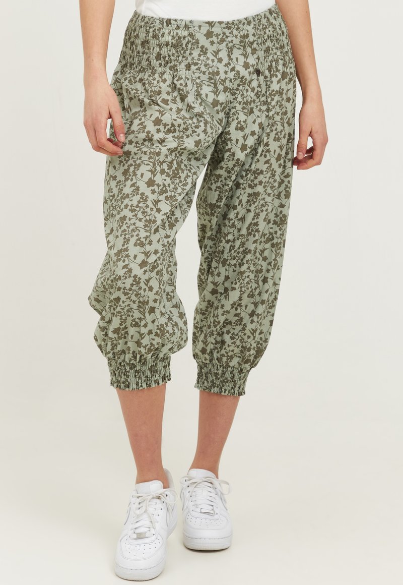 Letvægts, elastisk talje, cropped bukser i en afdæmpet grøn farve med et blomstermønster i mørkere grøn. Blødt stof med samlede ærmer.