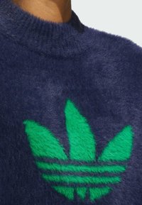 Marineblå, lodden genser med en fremtredende grønn Adidas-logo; har en rund halsutskjæring og myk, teksturert stoff.