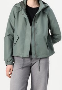 Light green waterproof jacket with a hood, adjustable drawstrings at the hem, side pockets, and front snap and zip closure.
