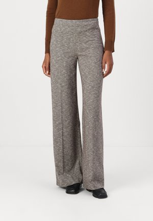 Videbukser i et struktureret gråt stof med høj talje og subtil houndstooth-mønster. Kombineret med en brun top og sorte sko.