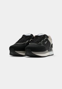 Svart og grå sneaker med teksturert overdel, kontrasterende gummisåle, rund tå og lagdelt design. Har snøring og logo-detalj.
