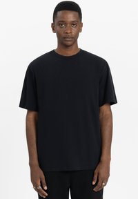 Zwart katoenen t-shirt met korte mouwen, ronde hals, ontspannen pasvorm, gladde textuur, geen zichtbare patronen of accenten.