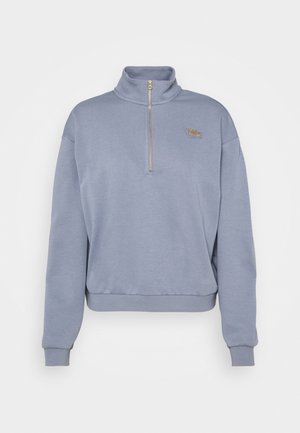 Jasnoniebieska bluza z długim rękawem, z półzamkiem przy kołnierzu i małym złotym logo Nike na lewej piersi.