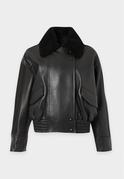 Μαύρο δερμάτινο μπουφάν bomber με μεγάλο μαύρο shearling γιακά, κουμπιά τυχεράκια, τσέπες με καπάκι και ελαστική μέση σε απλό φόντο.