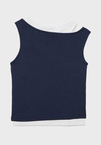 Marineblauer ärmelloser Stricktop, über einem weißen ärmellosen Hemd getragen, flach auf hellem Hintergrund ausgelegt.