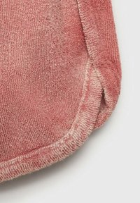 Rosa frottétyg med en mjuk, texturerad yta. Rundade kanter med vit sömdekoration längs sömmen.