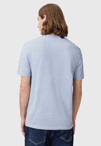Light blue T-shirt made of soft fabric, featuring a crew neckline and short sleeves. The back view shows a plain design with no logos.