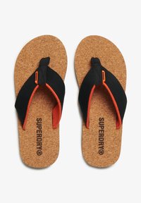 Zwarte teenslippers met een kurken voetbed, voorzien van oranje accenten en textielbandjes, met de merknaam "SUPERDRY" op de zool.