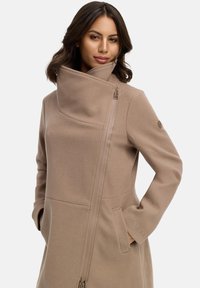 Beige Wollmischung Mantel mit hohem Kragen, diagonalem Reißverschluss, seitlichen Taschen und Logodetail am Ärmel. Glatte Textur und taillierte Passform.