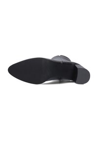Zwarte hakboot met een gladde, leerachtige afwerking, voorzien van een spitse neus en een dikke hak. De zool vertoont een geribbelde textuur voor grip.