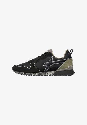 Baskets noires et vert olive avec un design à lacets, une semelle texturée à motif camouflage, et un logo en forme d'éclair stylisé sur le côté.