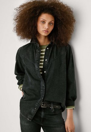 Mustast denimist särk, millel on nööpidega esitise, kaelaosa detailid ja üle mõõtude sobivus. Sügaval olnud koos triibulise rohelise ja valge pika varrukaga sormiga all.