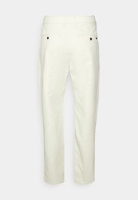 Světlé béžové kalhoty s hladkou texturou, rovnými nohavicemi, poutky na pásek a dvěma zadními kapsami s hnědými knoflíky.