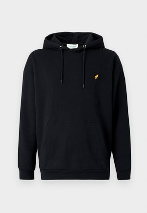 Melnas kokvilnas kapuces džemperis ar priekšējām kabatām, ar mazu dzeltenu putnu uz kreisā krūškurvja. Kapuces auklu detaļa.