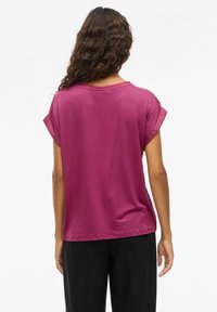 Magenta t-shirt z krótkim rękawem, o luźnym kroju i podwiniętych rękawach, wykonany z miękkiego materiału, z gładkim tyłem i zaokrąglonym dekoltem.