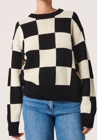 Schwarzer und cremefarbener kariertes Strickpullover mit geripptem Halsausschnitt und Saum, ausgestattet mit herabgesetzten Schulternähten und einer lockeren Passform.