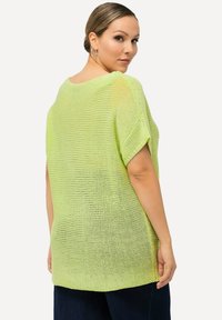 Strickpullover in leuchtendem Limettengrün, mit einer lockeren, atmungsaktiven Textur und kurzen Ärmeln, runden Ausschnitt und lässiger Passform.