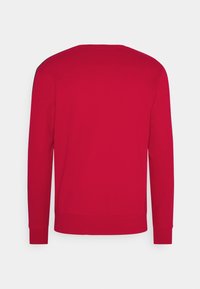 Maglione rosso con scollo rotondo, maniche lunghe, polsini e orlo a coste. Texture liscia con dettagli di cuciture minime sulle spalle.