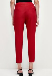 Pantalones rojos ajustados con un corte slim, cintura alta y detalle en el bolsillo trasero, fabricados con una tela suave y ligera.