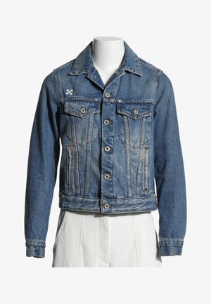 Veste en jean bleue avec fermeture par boutons, deux poches poitrine à rabat, poches latérales et un petit logo blanc brodé sur la poitrine gauche.