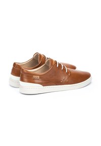 Zapatos de cuero marrón con un acabado texturizado, cordones blancos y una gruesa suela de goma blanca, con costuras sutiles y detalles de marca.